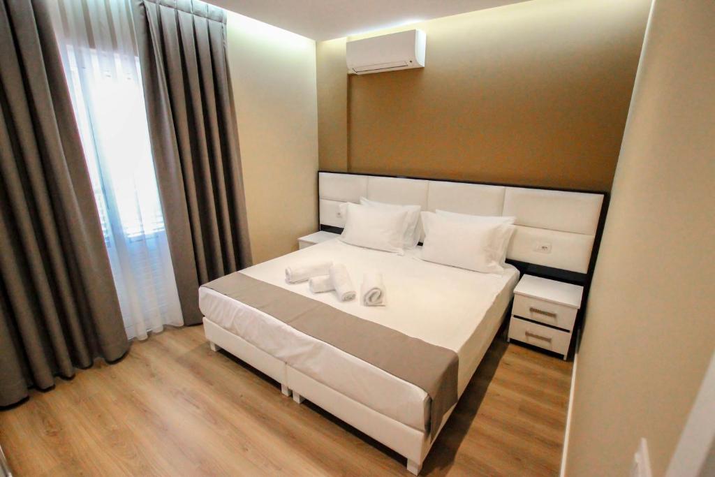 Un dormitorio con una gran cama blanca y una ventana en Brilant Luxury Apartment, en Gjirokastra