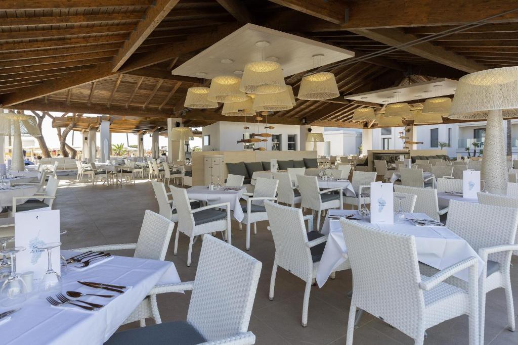 a restaurant with white tables and chairs and chandeliers at Hipotels Barrosa Park in Chiclana de la Frontera