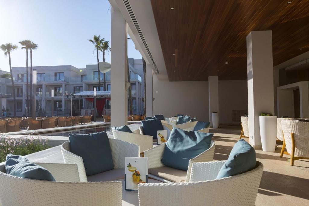a row of chairs with blue pillows on a patio at Hipotels Barrosa Park in Chiclana de la Frontera