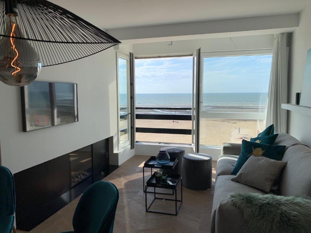 een woonkamer met een bank en uitzicht op het strand bij Seashore Beach View in Koksijde