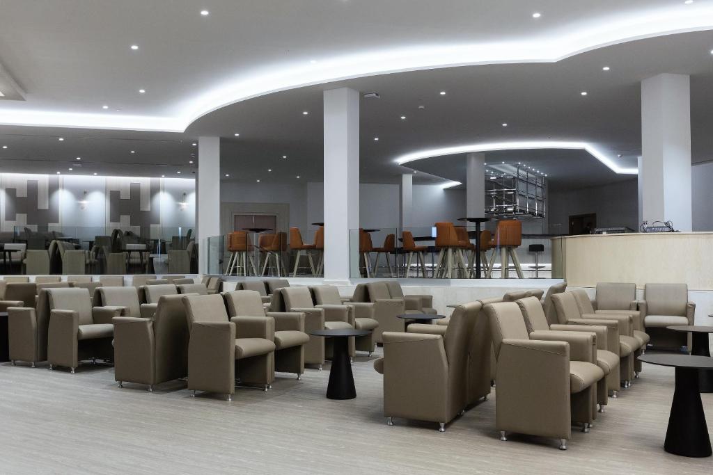 a waiting room with chairs and tables and a bar at Hipotels Barrosa Park in Chiclana de la Frontera