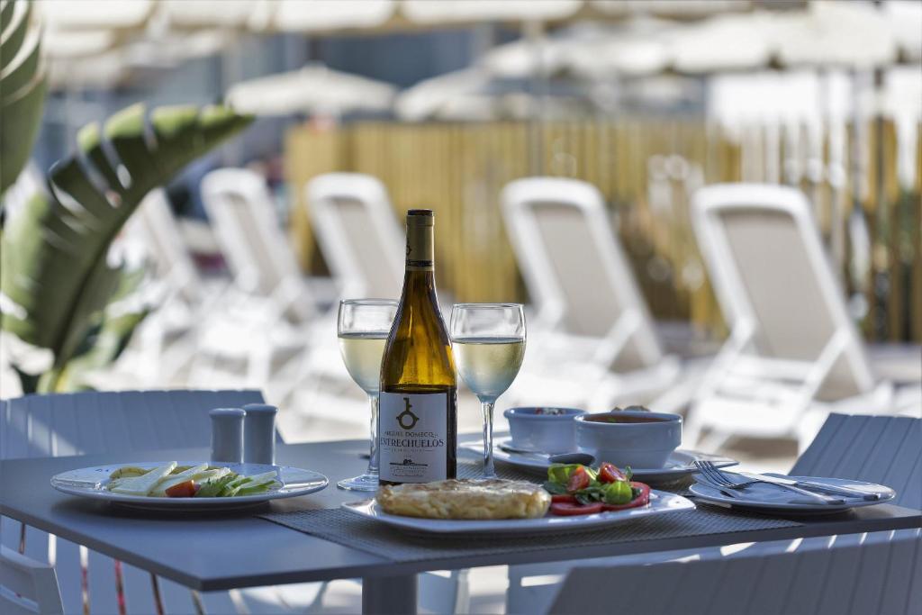 a table with a bottle of wine and a plate of food at Hipotels Barrosa Park in Chiclana de la Frontera
