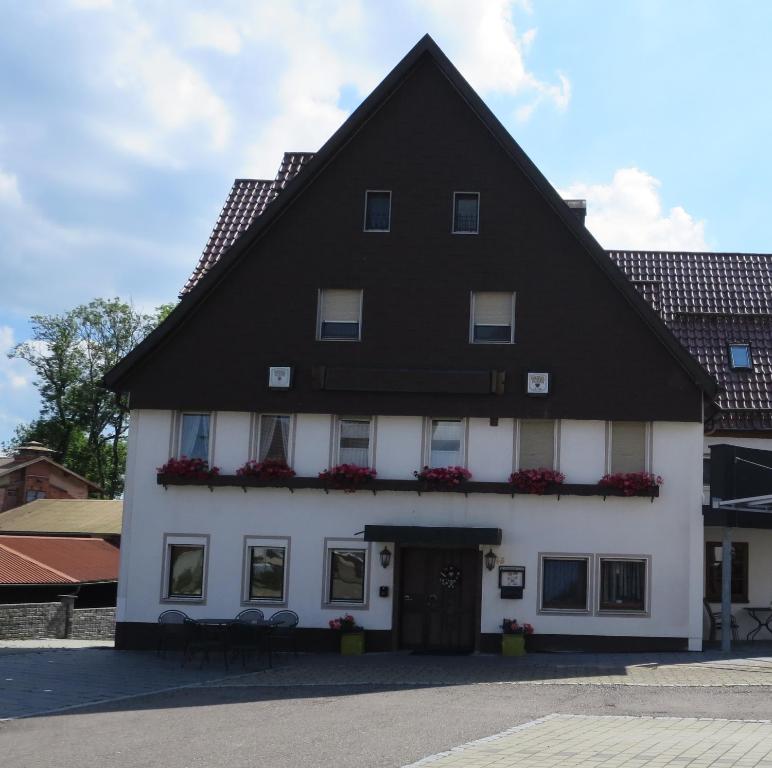 ein großes weißes Gebäude mit schwarzem Dach in der Unterkunft Der Gasthof in Alfdorf in Alfdorf