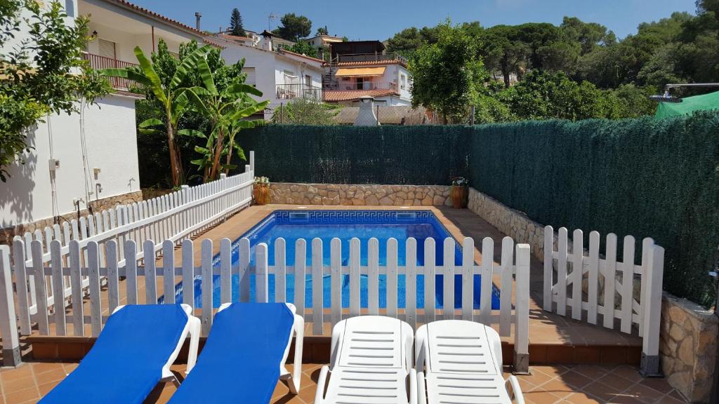 einen Pool mit zwei Gartenstühlen und einem Paar in der Unterkunft Azahara in Lloret de Mar