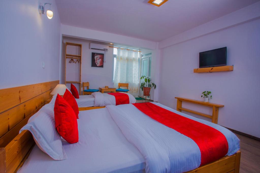 a bedroom with two large beds with red pillows at Mount Princess Hotel in Dhulikhel