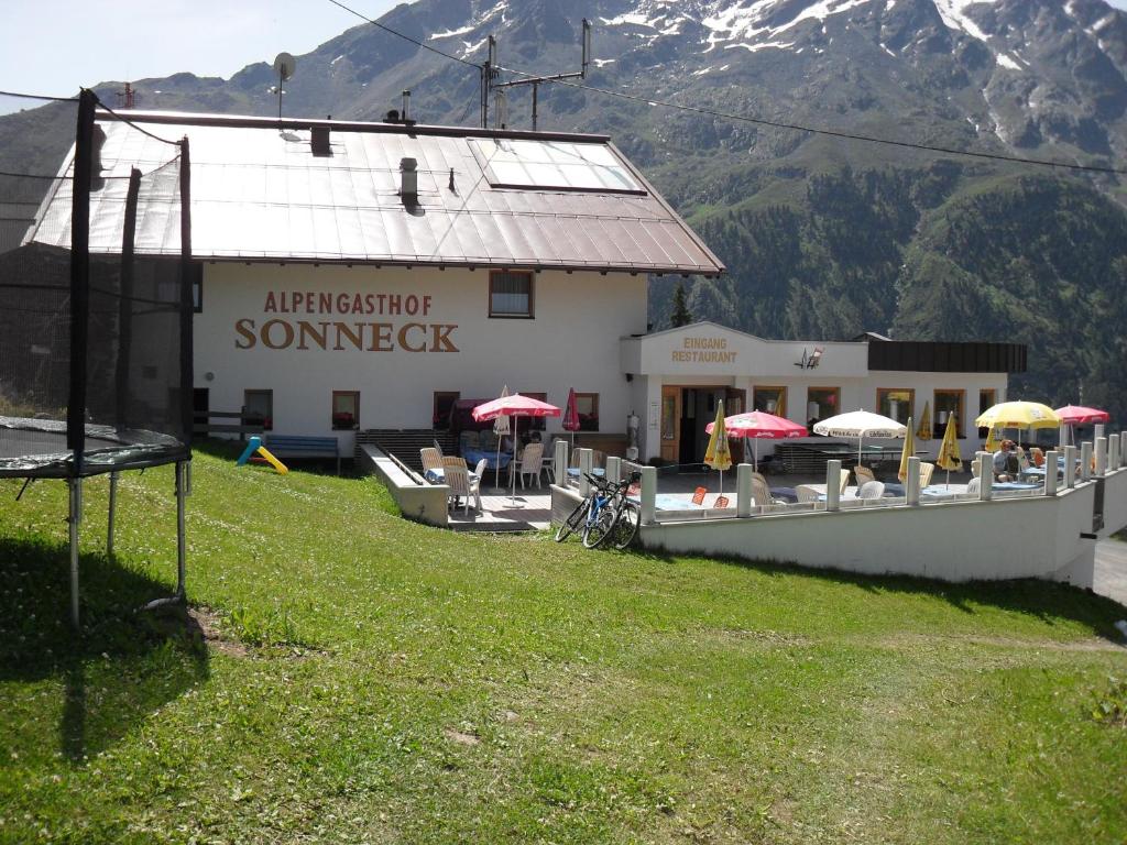 a building with umbrellas in front of a mountain at Alpengasthof Sonneck in Sölden