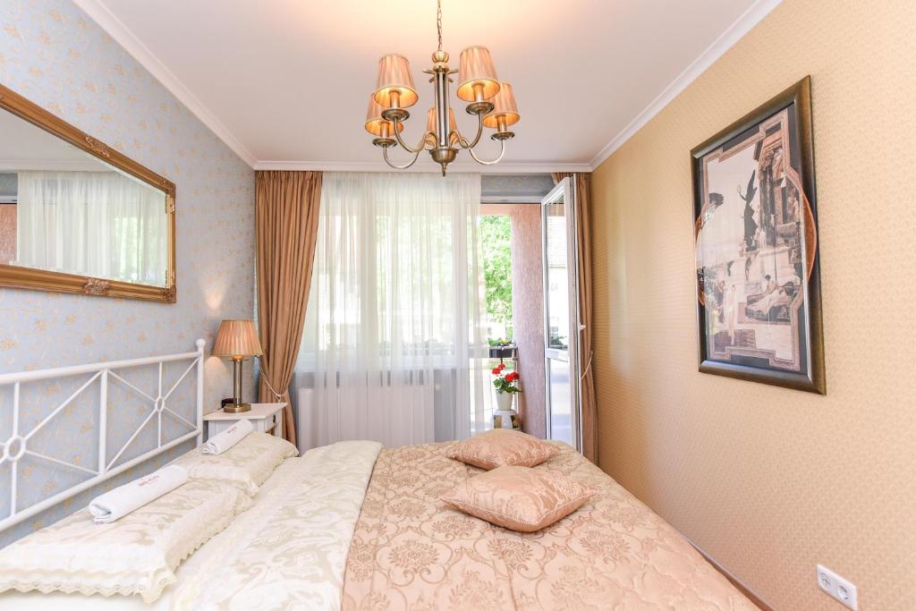 a bedroom with a bed and a chandelier at 2 kambarių apartamentai su virtuve, Trakų miesto centre in Trakai