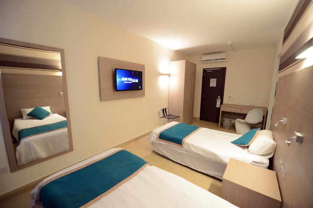 a hotel room with two beds and a mirror at Day's Inn Hotel and Residence in Sliema