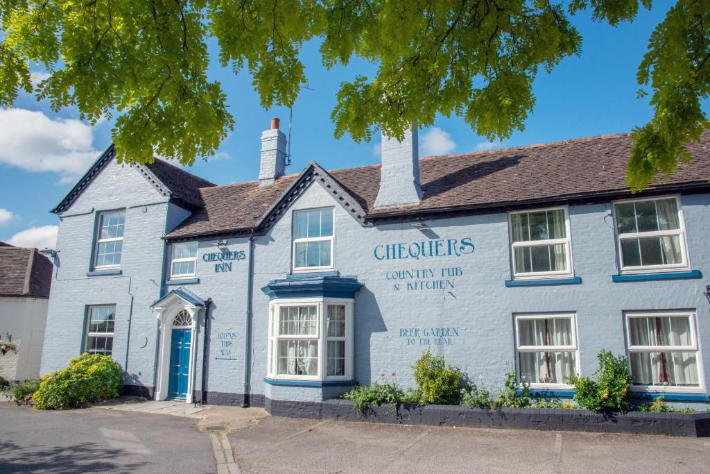 a white building with a blue door at Chequers Inn in Fladbury
