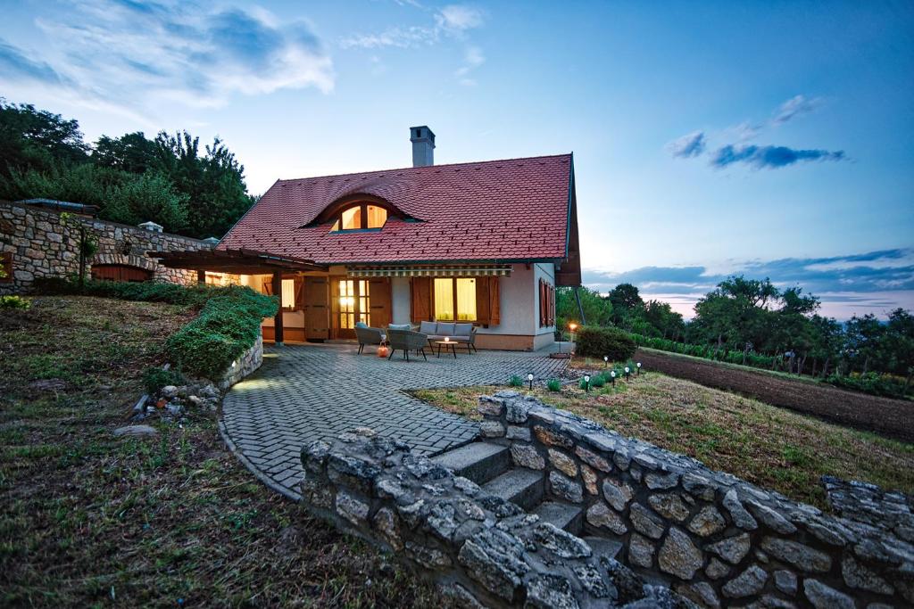 a house with a stone wall and a patio at Öreghegyi Panoráma Villa, Balatonederics in Balatonederics