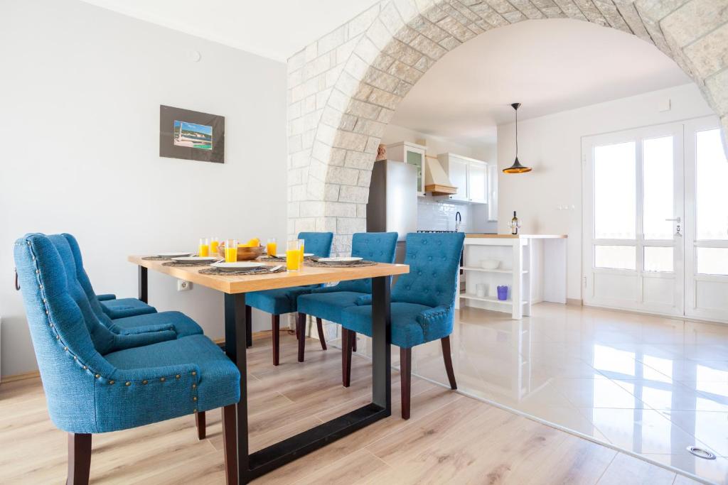 uma cozinha e sala de jantar com uma mesa de madeira e cadeiras azuis em Holiday apartment IVICA em Milohnići