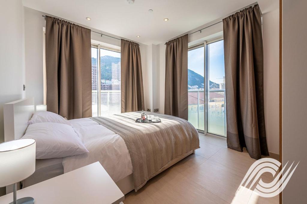 a hotel room with a bed, table, and window at Westone Luxury Self Catered Apartments in Gibraltar