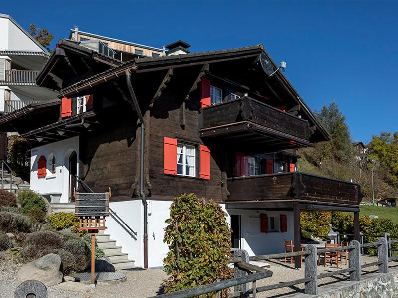 ein Haus mit roten Fensterläden und einem Balkon in der Unterkunft Casa Vesta Magnifica Wildi in Brigels