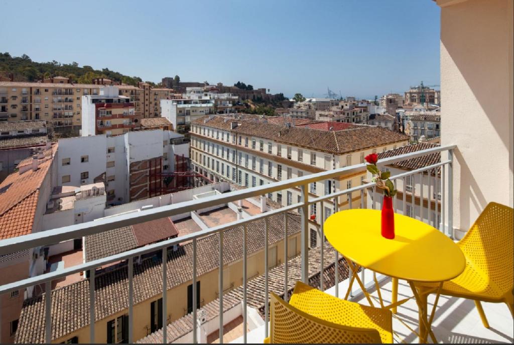 een gele tafel en stoelen op het balkon van een gebouw bij La Merced RooMalaga by Bossh! Apartments in Málaga