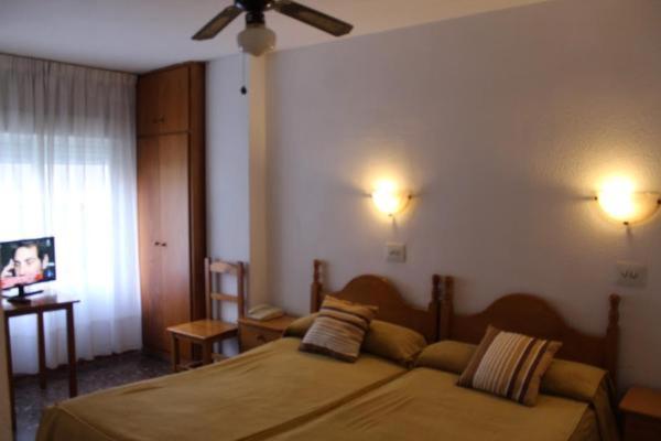 a bedroom with a bed and a ceiling fan at Pension Americano in Almería