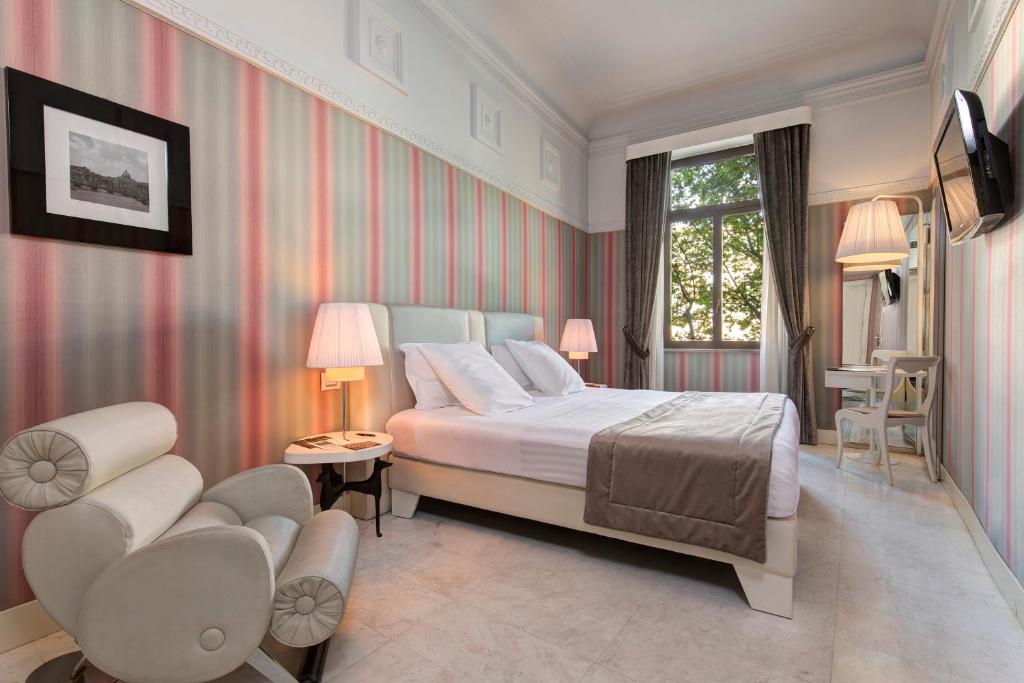 a bedroom with a bed and chairs and a window at Grand Hotel Palace Rome in Rome
