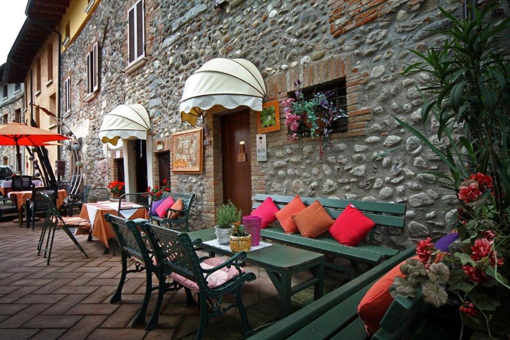 patio ze stołami i krzesłami oraz kamienny budynek w obiekcie AL BORGO ANTICO Ristorante con camere w mieście bedizzol