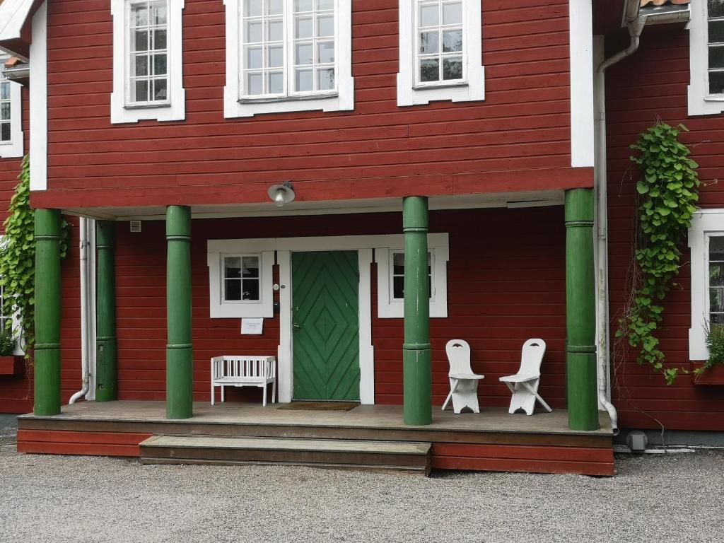 una casa roja con 2 sillas blancas en el porche en Stockholm B&B Cottage en Nacka