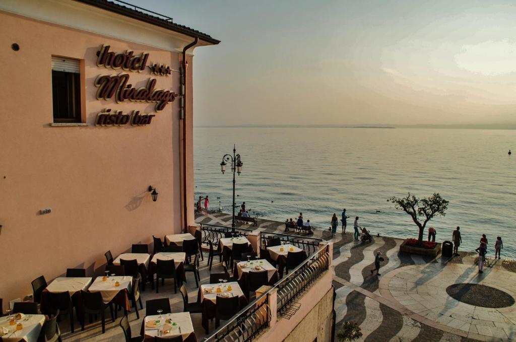 a restaurant with tables and a view of the water at Hotel Miralago in Lazise