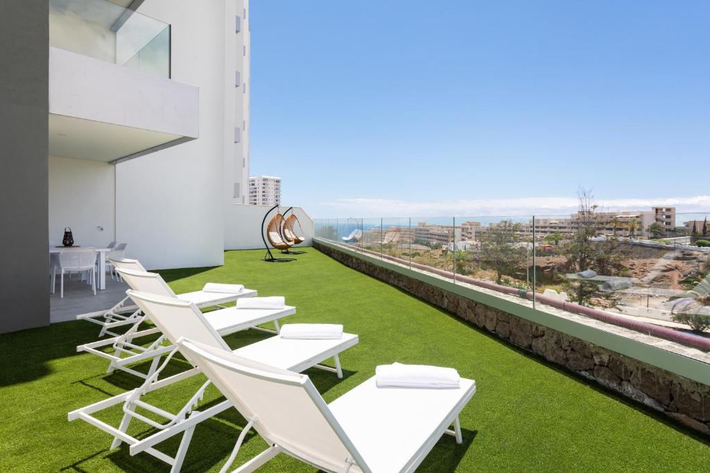 een rij witte ligstoelen op het dak van een gebouw bij Oceanfront Rental in Adeje