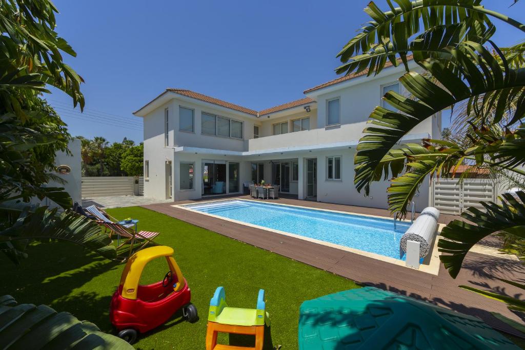 ein Haus mit einem Pool und einem Hof mit einem Spielzeugauto in der Unterkunft Larnaca Villa Marisol Kiti in Larnaka