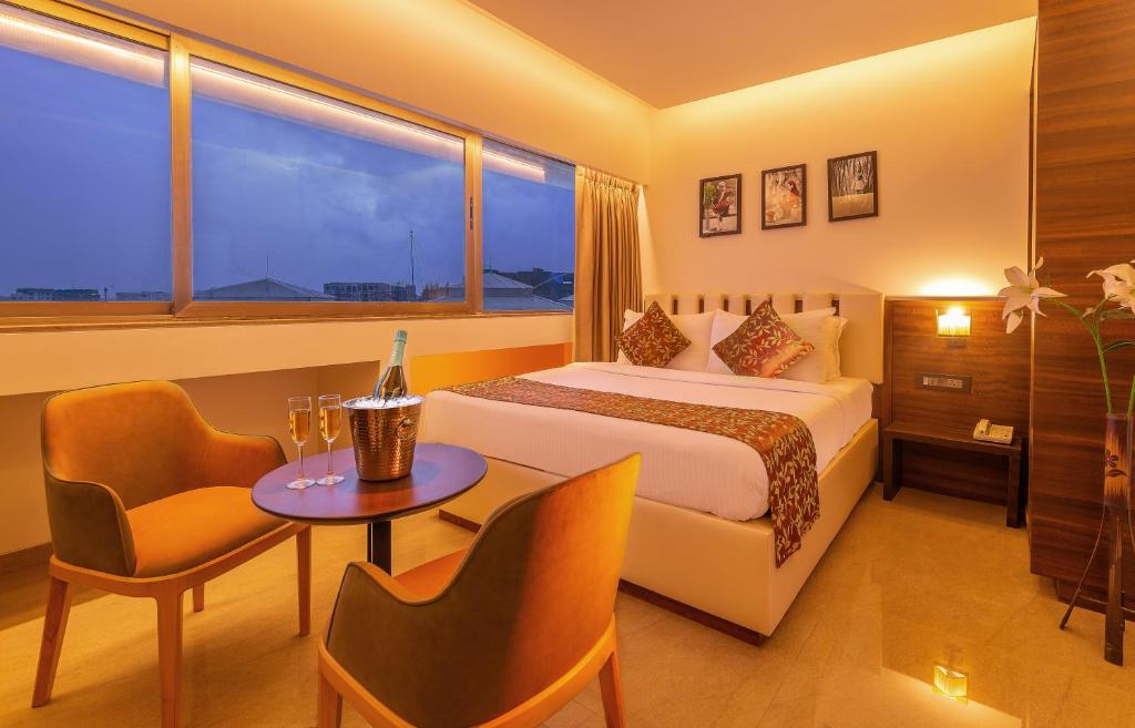 a hotel room with a bed and a table and chairs at Hotel Metropole Inn in Mumbai