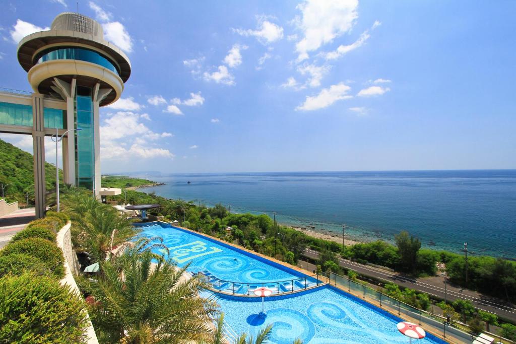 uitzicht op een zwembad met een toren en de oceaan bij H Resort in Checheng