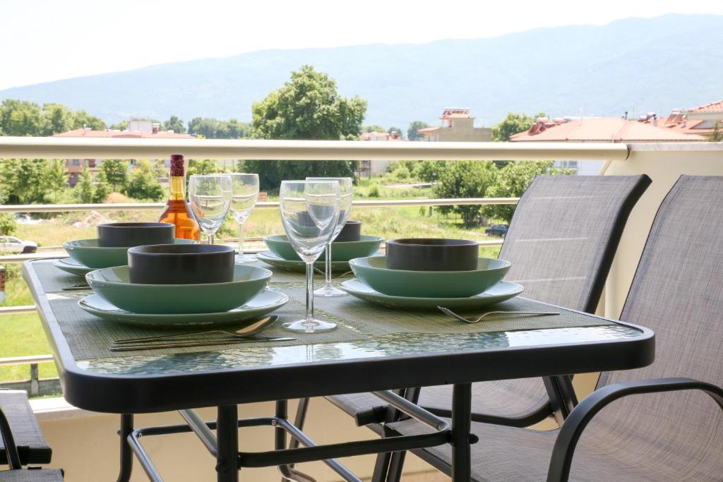 een tafel met borden en wijnglazen op een balkon bij Green Apartment in Leptokaria in Leptokarya