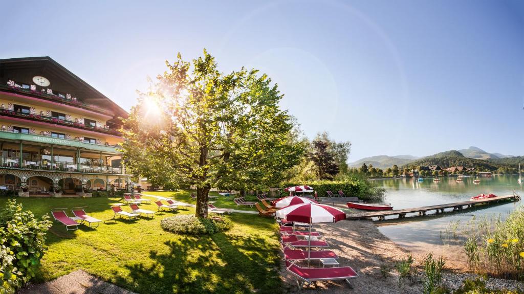 a river with chairs and a boat on the water at Hotel Seewinkel in Fuschl am See