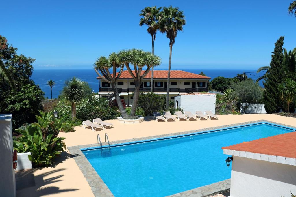 una piscina frente a una casa con el océano en Apartamentos Miranda en Breña Alta