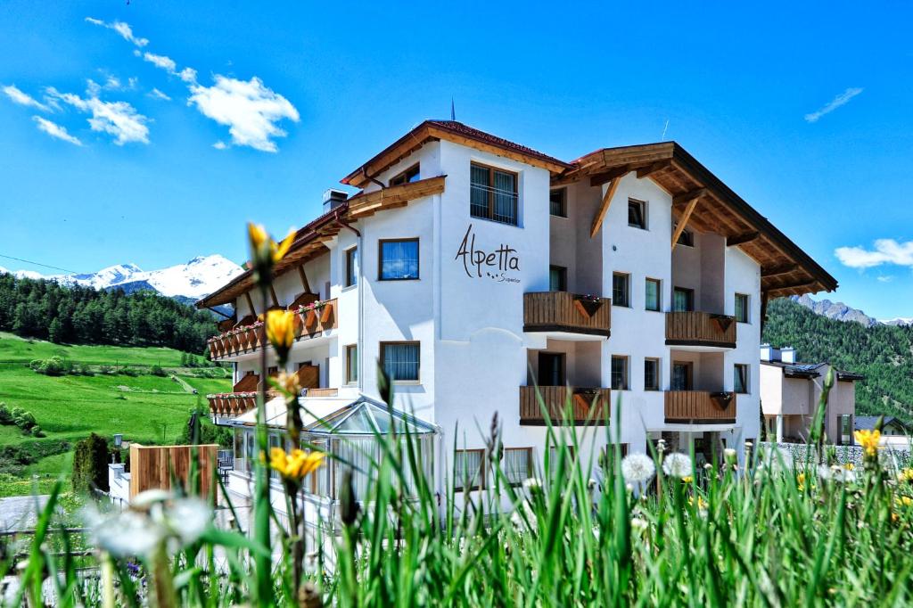 un hotel en las montañas con flores en primer plano en Alpen Boutique Hotel Alpetta, en Nauders