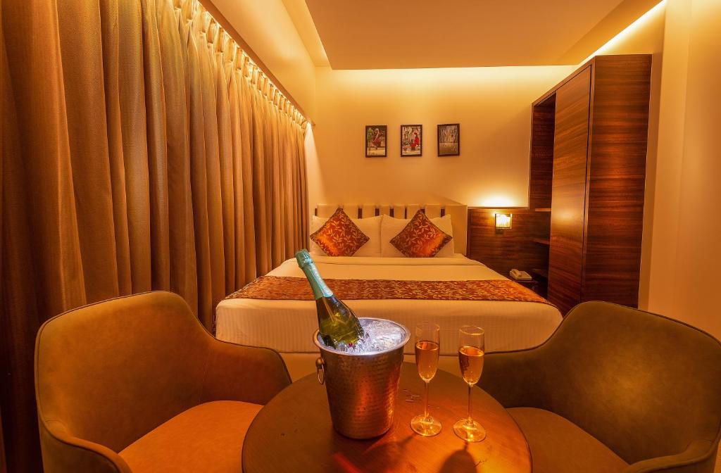 a hotel room with a bed and a bottle of wine on a table at Hotel Metropole Inn in Mumbai