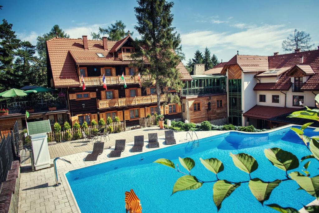 a house with a pool and lawn chairs at Hotel Modrzewiówka in Lanckorona