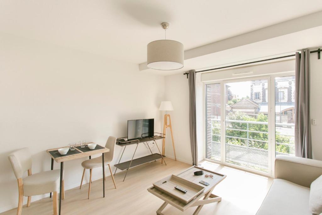 sala de estar con sofá, mesa y ventana en Zenao Appart'hôtels Troyes en Troyes