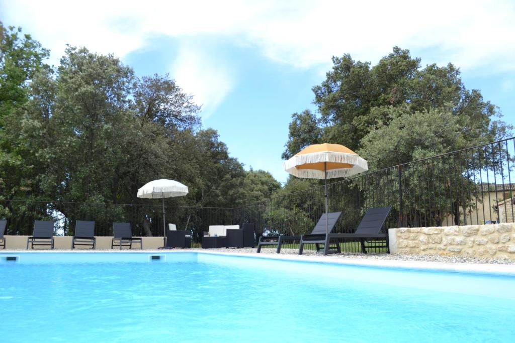 una piscina con sillas y sombrilla en La Romagnolette, en Saint-Restitut
