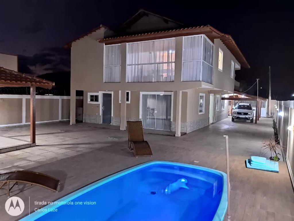 a villa with a swimming pool in front of a house at Casa com conforto e segurança in Rio das Ostras