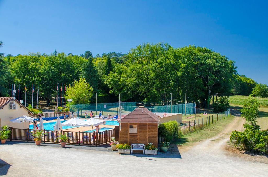 a swimming pool with a building next to a fence at Camping Paradis de Maillac in Sainte-Nathalène