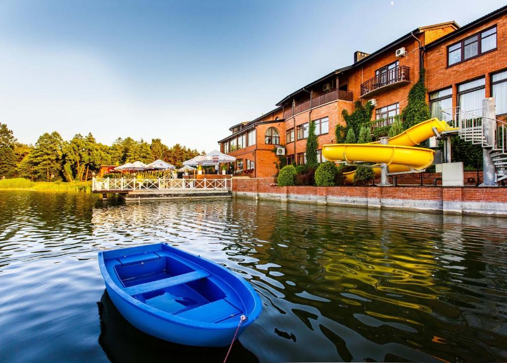 ein blaues Boot im Wasser neben einer Wasserrutsche in der Unterkunft Hotel Duo Spa in Janów Lubelski