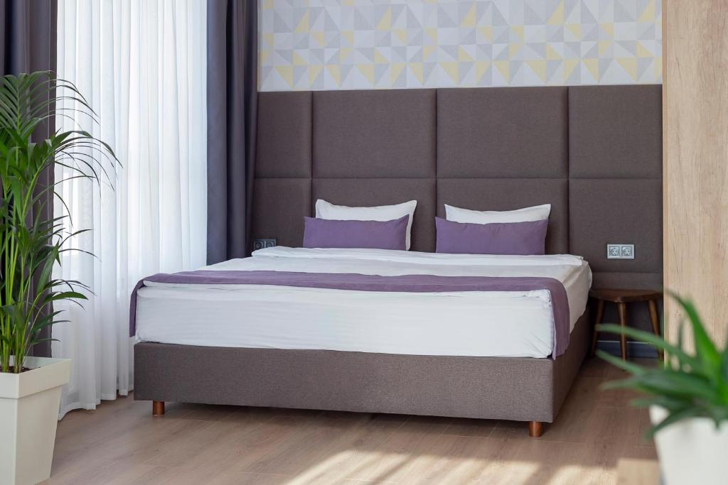 1 dormitorio con 1 cama grande con almohadas moradas en ApartUA Кропивницький, en Kropyvnytskyi