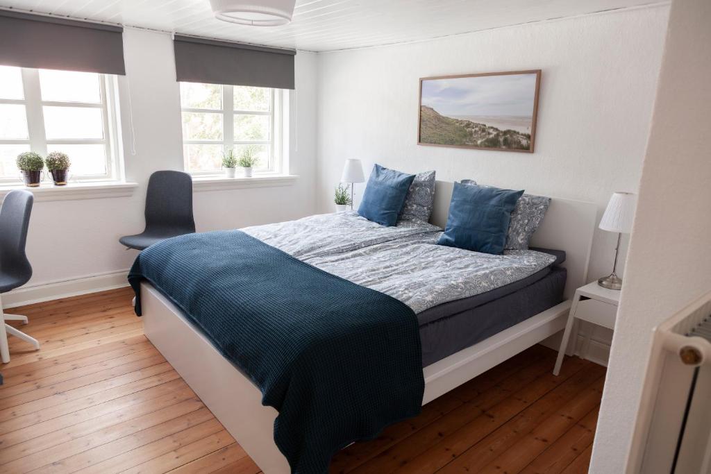 a bedroom with a large bed with blue pillows at Like home Bed & Breakfast in Varde