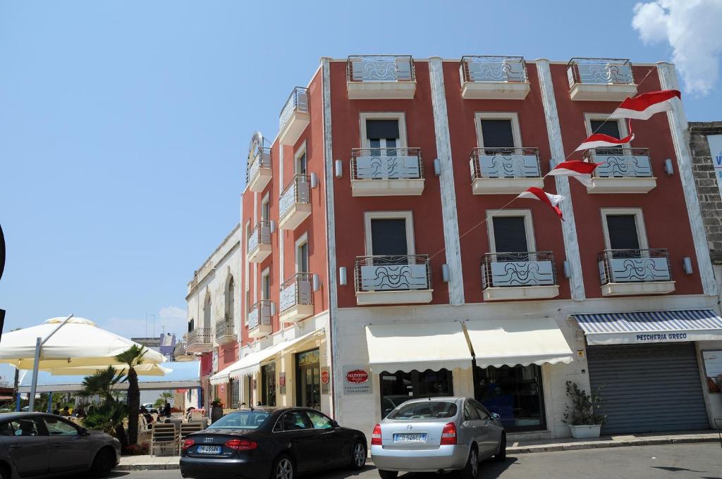a red building with cars parked in front of it at Hotel Miramare in Porto Cesareo