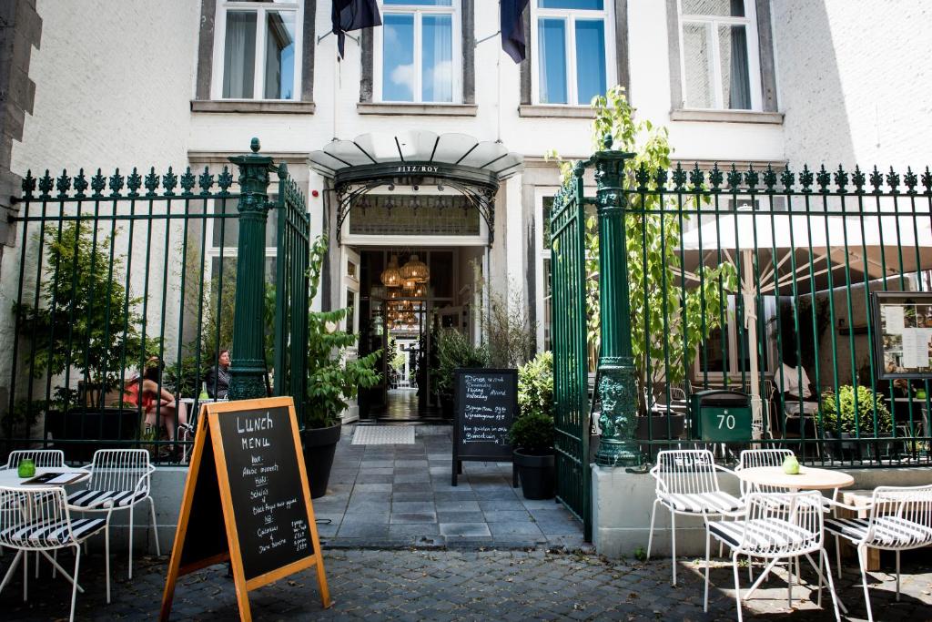 Fitz Roy Urban Hotel, Bar and Garden في ماستريخت: مطعم فيه طاولات وكراسي امام مبنى