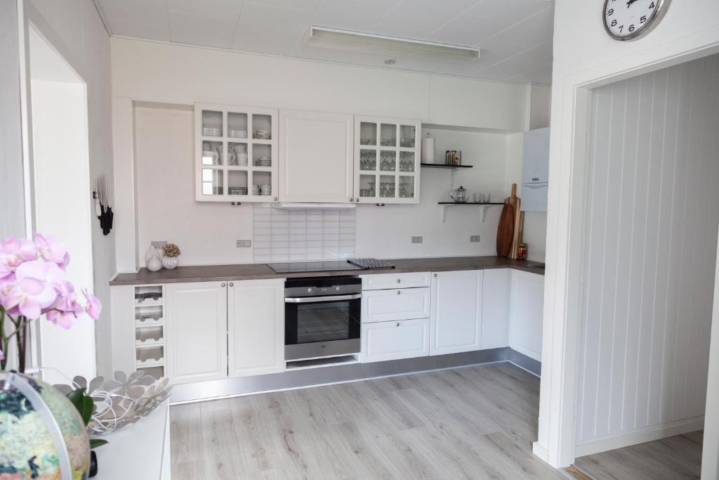 a kitchen with white cabinets and a clock on the wall at Like home Holiday House 9 A in Varde
