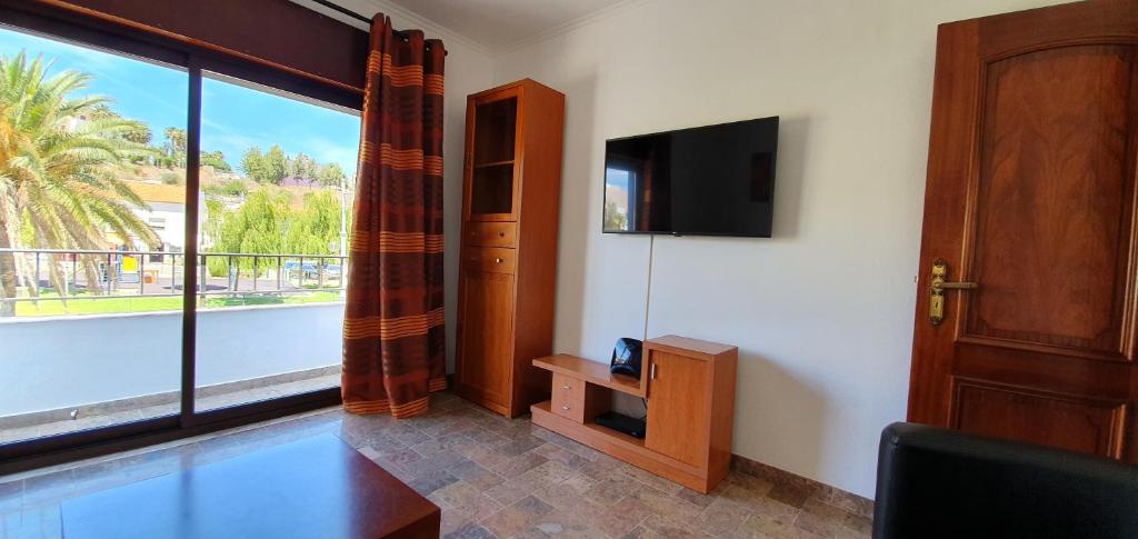 sala de estar con ventana grande y TV en Keep Calm Apartments, en Ferragudo