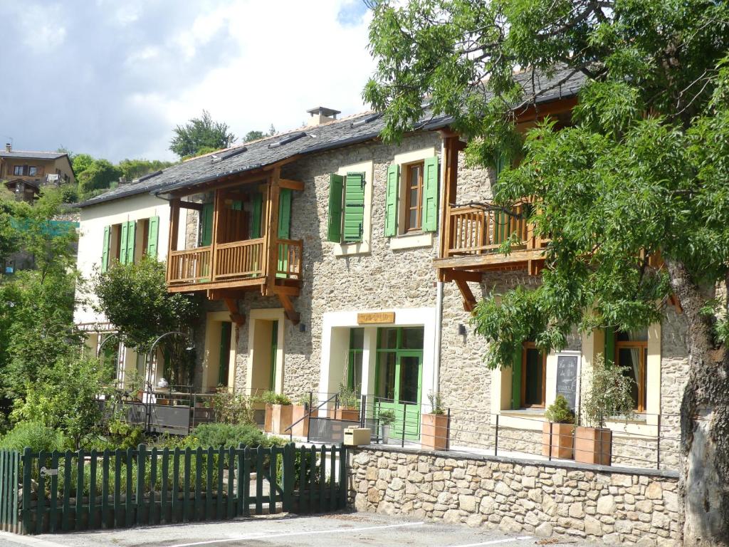 una casa de piedra con persianas verdes y una valla en Gîte de Llo Eco-hébergement de montagne, en Llo