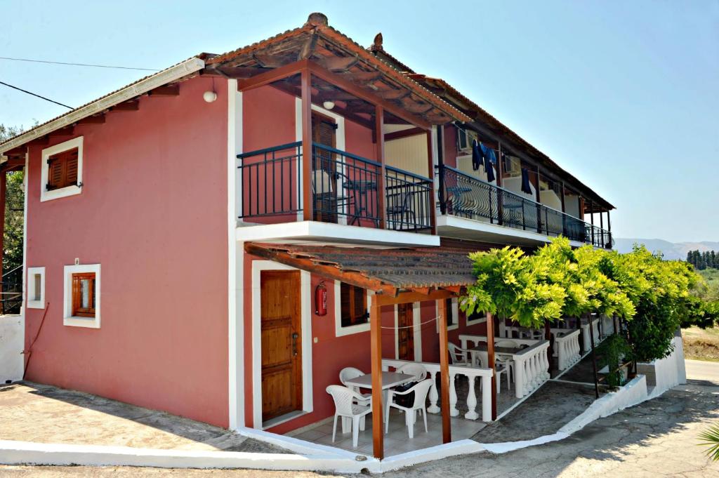 una casa rossa con balcone, tavoli e sedie di Studios Dimitris Giatras a Città di Zante