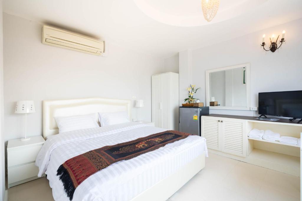 a white bedroom with a bed and a television at Baan Anodat in Ban Bang Phai