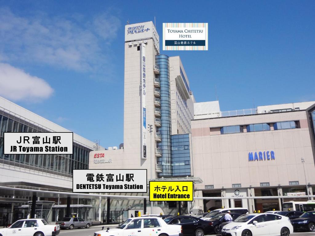 Toyama Chitetsu Hotel في توياما: مبنى ابيض كبير عليه لافتات