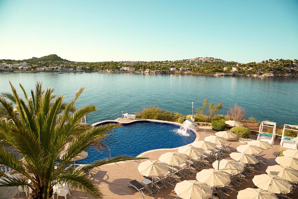 a swimming pool with umbrellas and a body of water at Sentido Fido Punta del Mar Hotel & Spa - Adults Only in Santa Ponsa