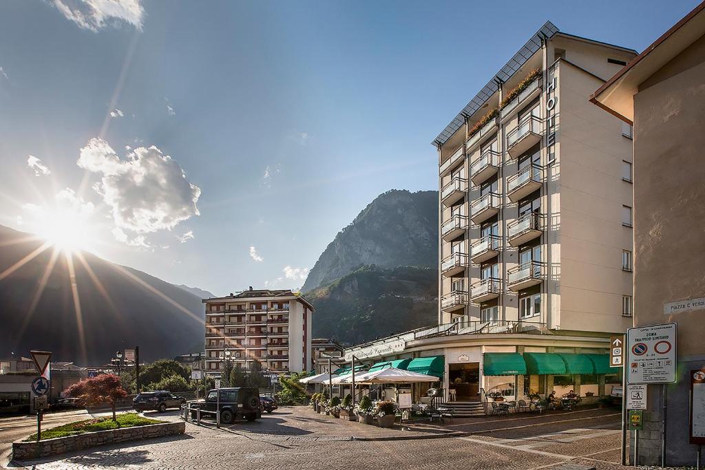 ein Gebäude in einer Stadt mit einem Berg im Hintergrund in der Unterkunft Hotel Conradi in Chiavenna
